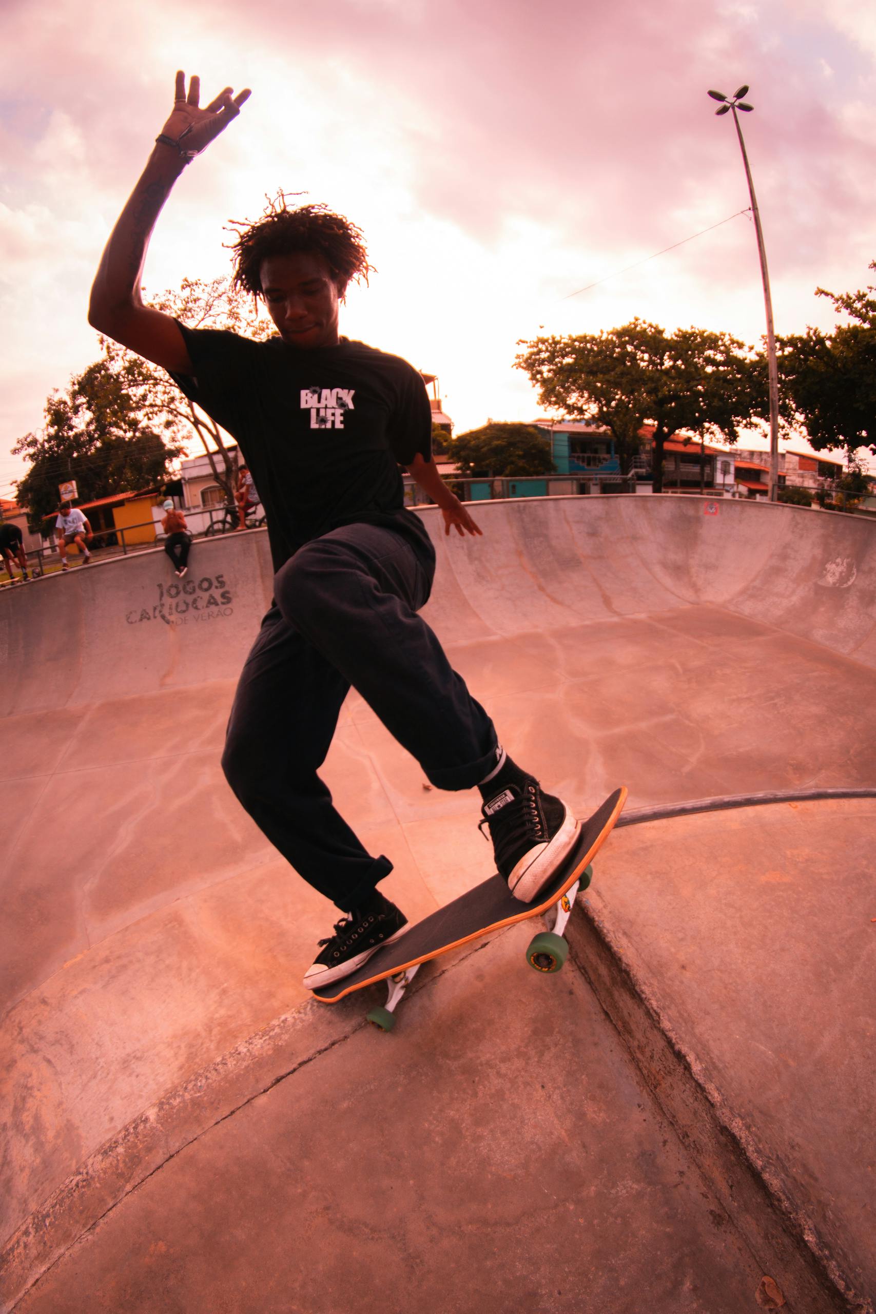 A young skateboarder performs a trick at an urban skate park during sunset.