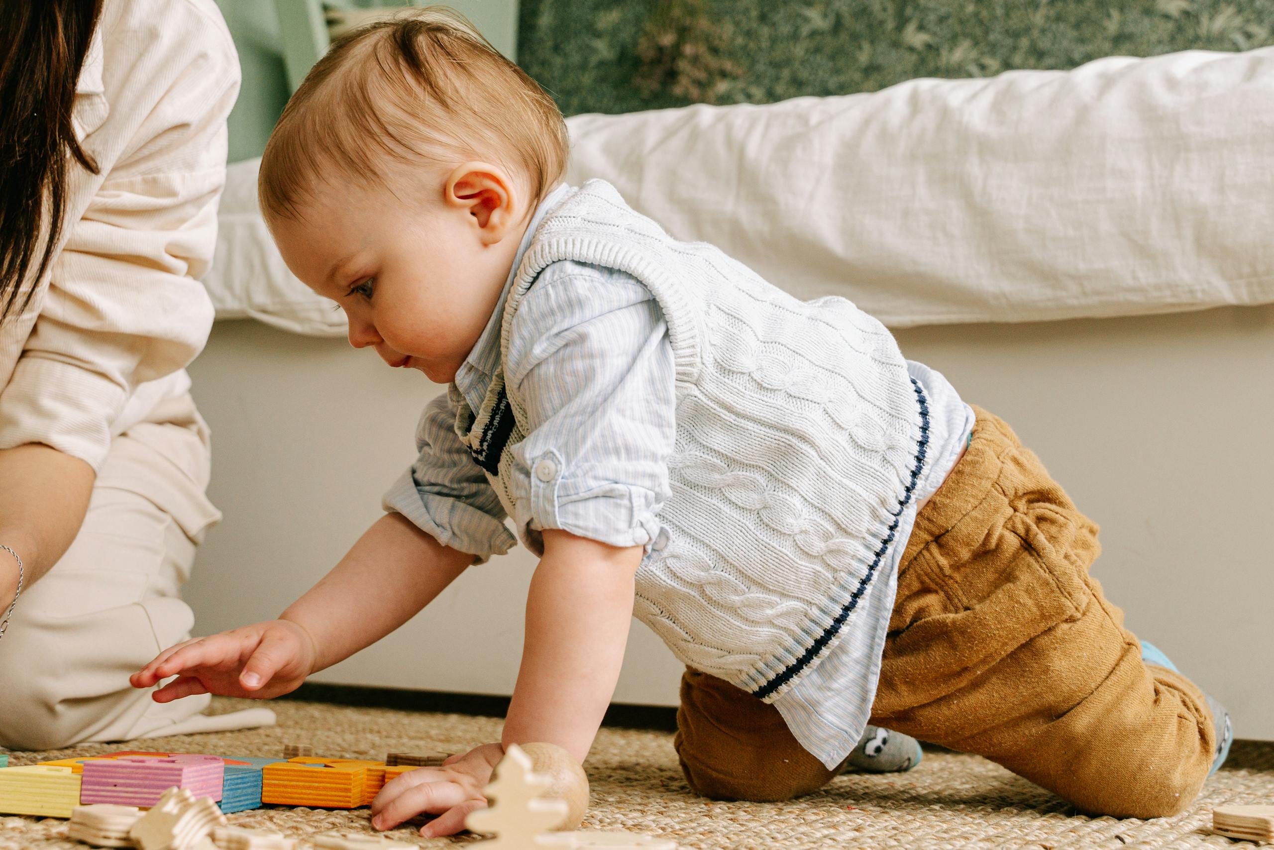 Charming scene of a joyful baby boy engaging with colorful wooden blocks on the floor.