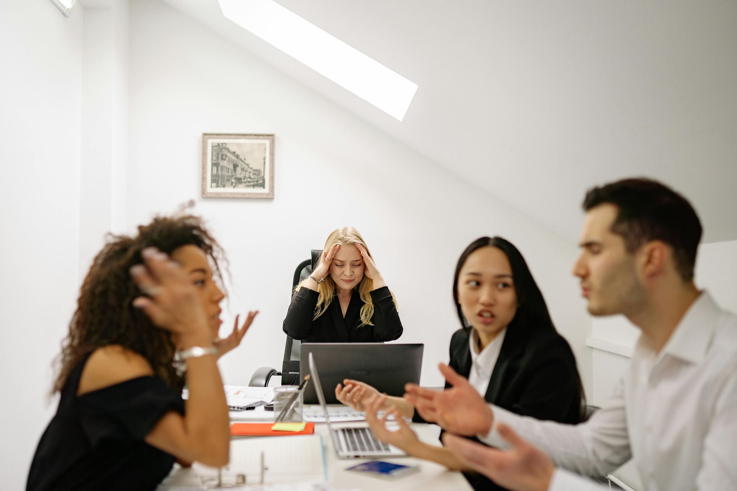 Colleagues in a heated discussion around a desk, highlighting workplace stress and tension.