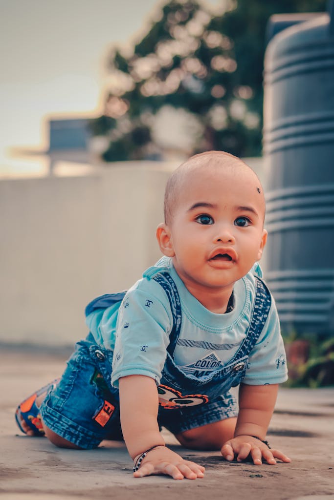 Cute baby in denim overalls crawling outdoors. Ideal for child development concepts.