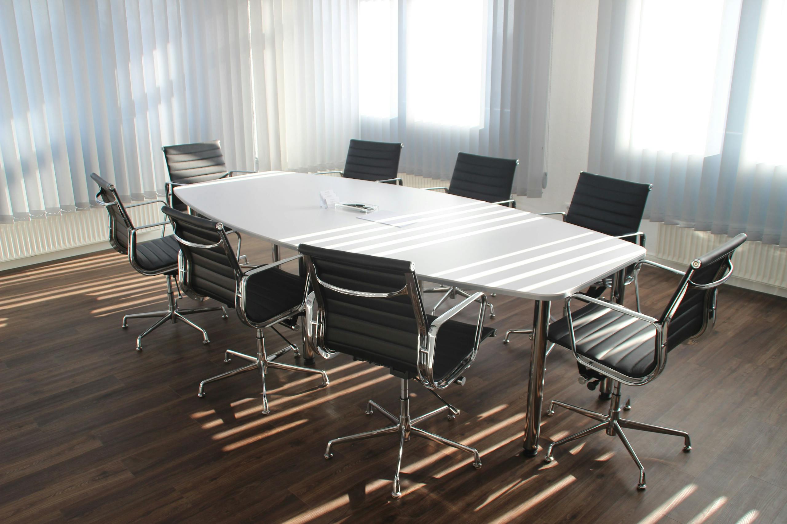 Modern office meeting room with designer chairs, table, and large windows.